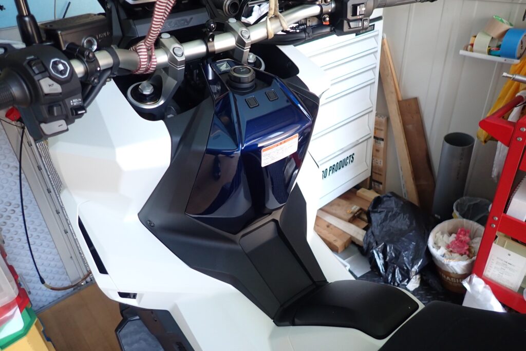 Top view of the Honda X-ADV center cowl console panel surrounding the fuel cap and main ignition switch before disassembly.