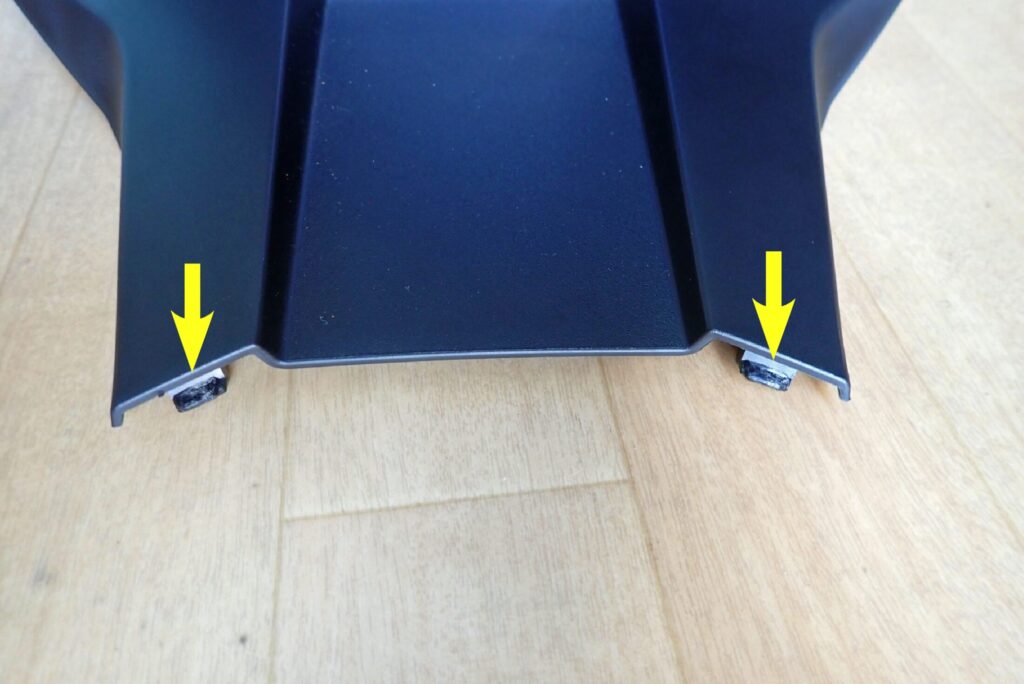 Yellow arrows indicating the lower locking tab protrusions on the tip of the center console cowl.