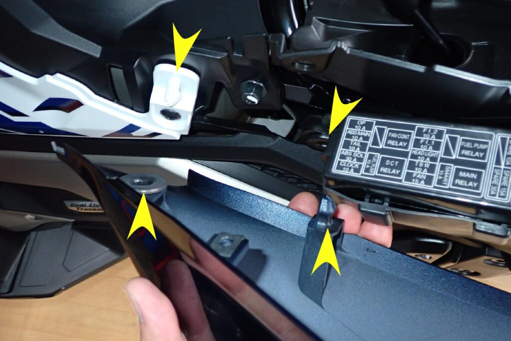 Yellow arrows showing the white chassis grommet holder and the plastic mounting pin on the inner side of the Honda X-ADV rear cowl.