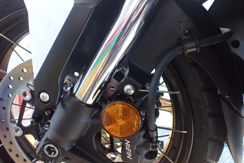 The right-side view of a Honda X-ADV front wheel area, showing the reassembled front fender, brake caliper, and gold fork.