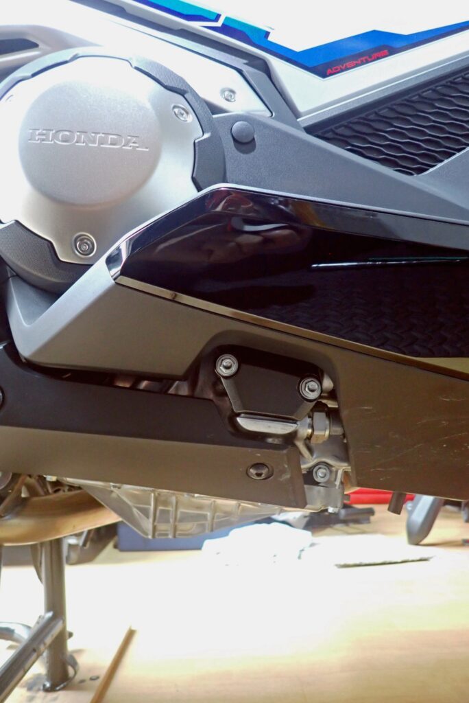 Looking up at the right under cowl panel of a Honda X-ADV, demonstrating how the plastic cover guards the internal transmission area.