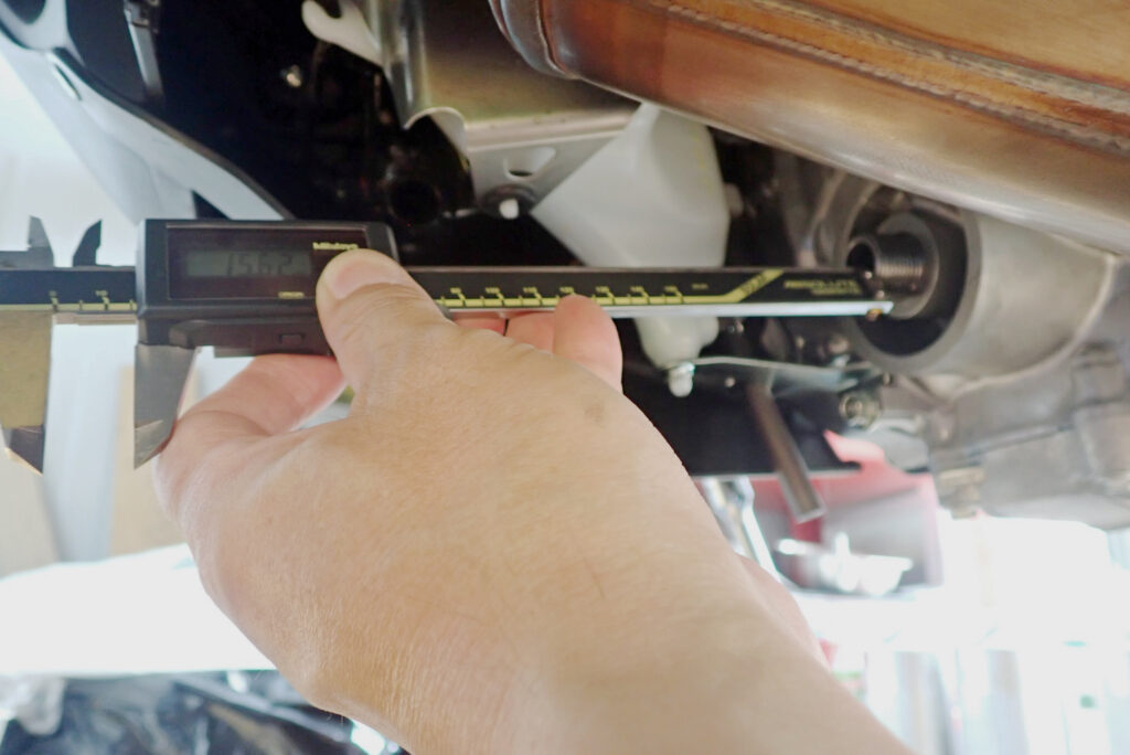 Using a digital caliper vernier tool to accurately measure the outer diameter thread of a Honda X-ADV oil filter mounting stud, showing 15.62 mm.