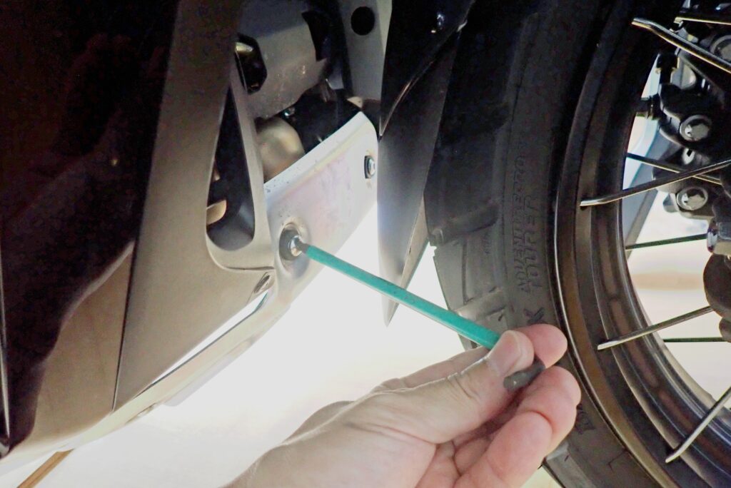 A hand using a Wera hex wrench l-key to loosen the socket bolts of the aluminum underguard on a Honda X-ADV.