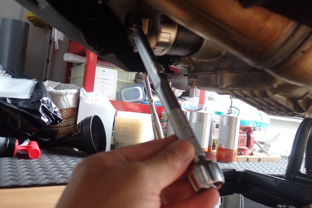 A mechanic using a torque wrench to precisely tighten the new engine oil filter cartridge to factory specifications.