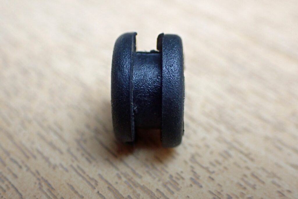 Detailed macro shot of the asymmetric rubber grommet showing the flat-edge side oriented toward the flanged metal bushing.