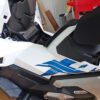 Overview of the white and blue left side body cowl panel on a Honda X-ADV motorcycle before removal.