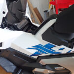 Overview of the white and blue left side body cowl panel on a Honda X-ADV motorcycle before removal.