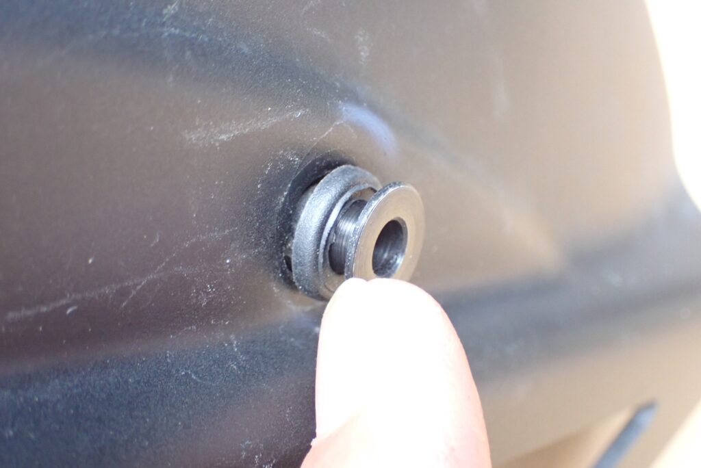 Finger inserting the flanged metal bushing sleeve into the center hole of the rubber grommet on the Puig hugger.