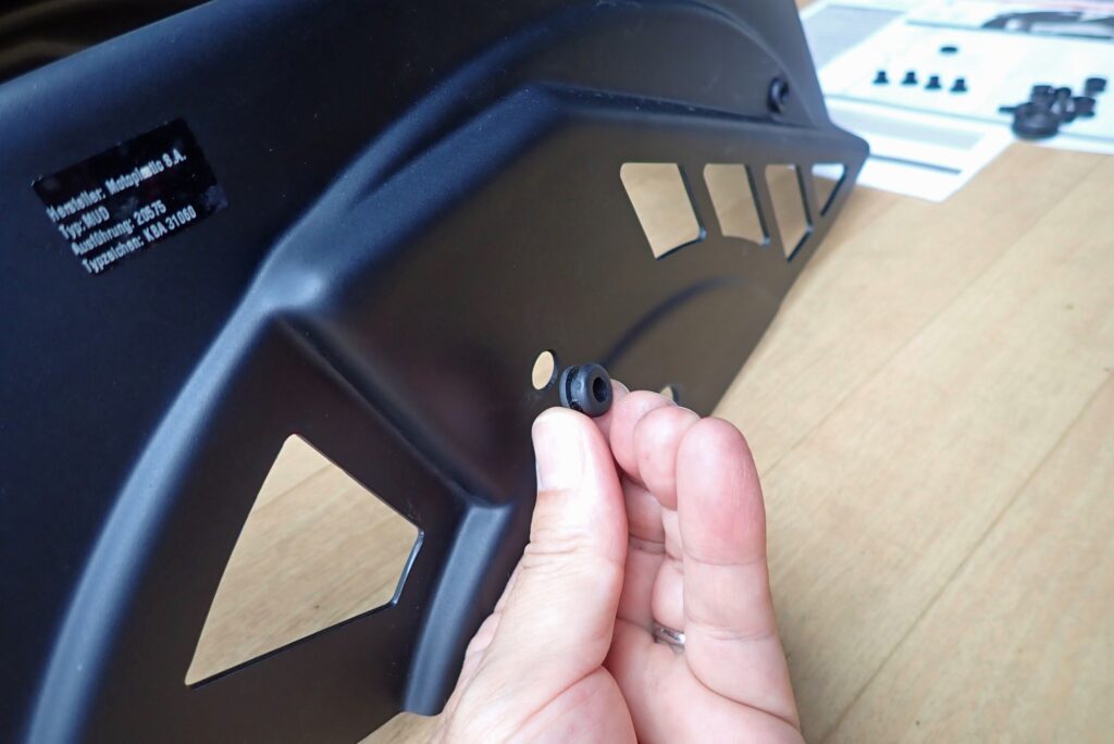Inserting a vibration-damping rubber grommet into the mounting hole of the Puig plastic splash guard body.