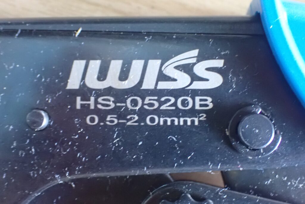 Macro shot of the IWISS logo and model number HS-0520B with wire gauge specs engraved on the black metal body of the tool.