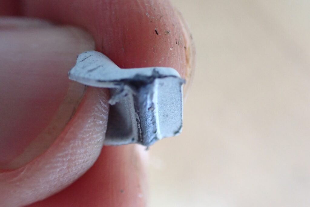 Close-up of the plastic cowl tab after grinding down the lower hook, creating a smoother profile to prevent future breakage.