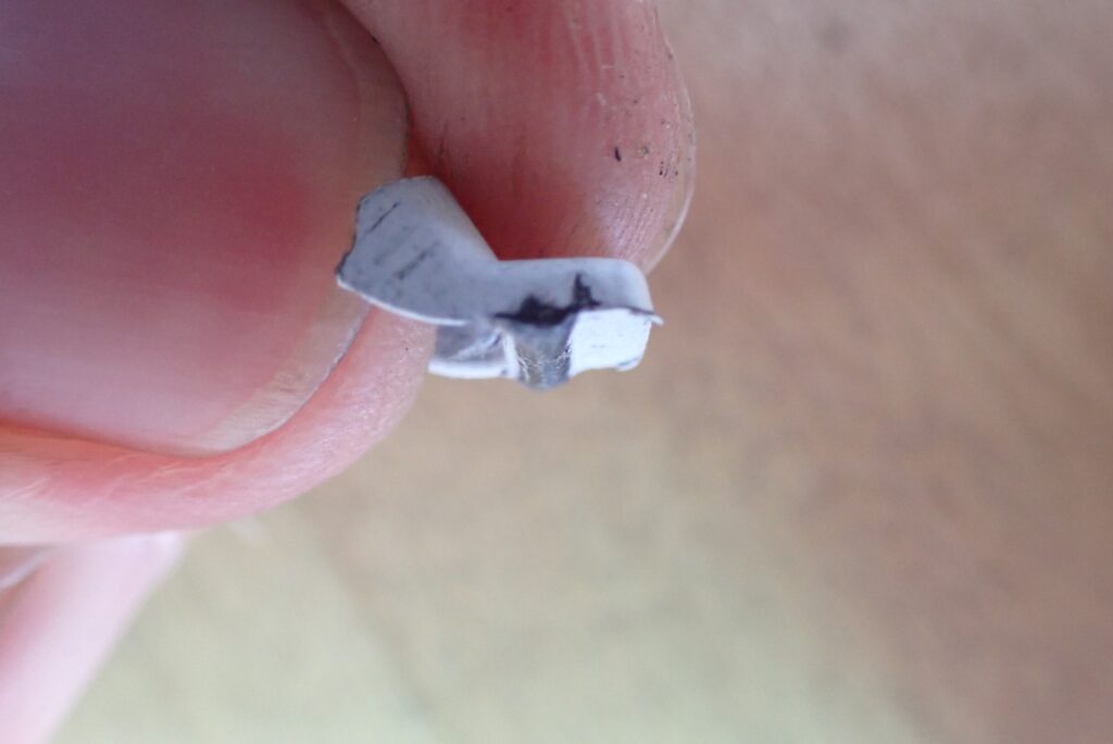 Angle view of the reshaped Honda X-ADV fairing tab ready to be reattached to the side cowl using plastic repair resin.