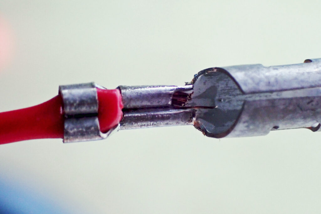Extreme close-up of a perfectly crimped female bullet terminal showing neat heart-shaped curls on both wire core and insulation.