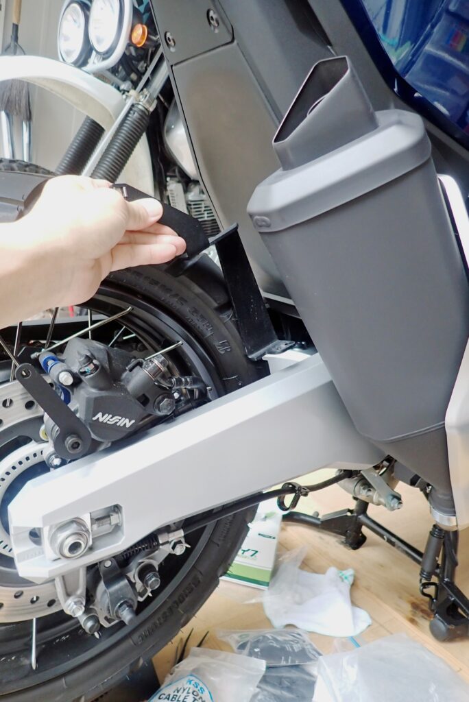 Fitting the heavy-duty Puig right-side main support bracket curving over the Honda X-ADV swingarm and exhaust.