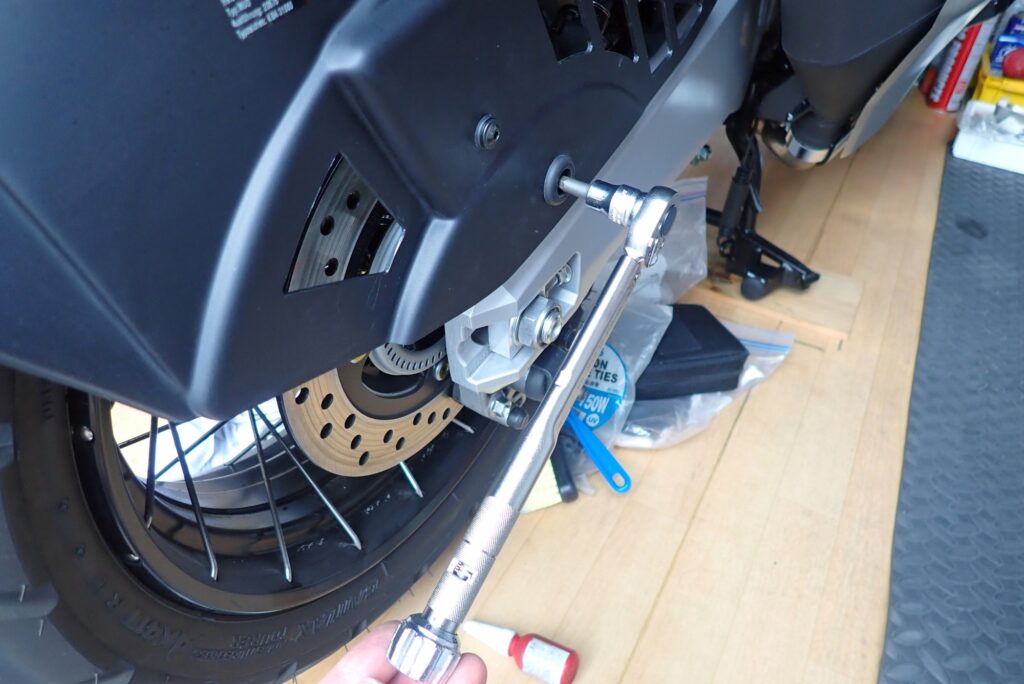 Tightening the rear brake caliper mounting bolt using a precision torque wrench on the Honda X-ADV.