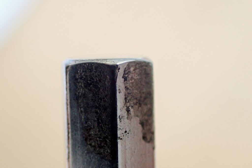 Macro close-up of TONE 5mm hex bit tip showing chrome plating peeling