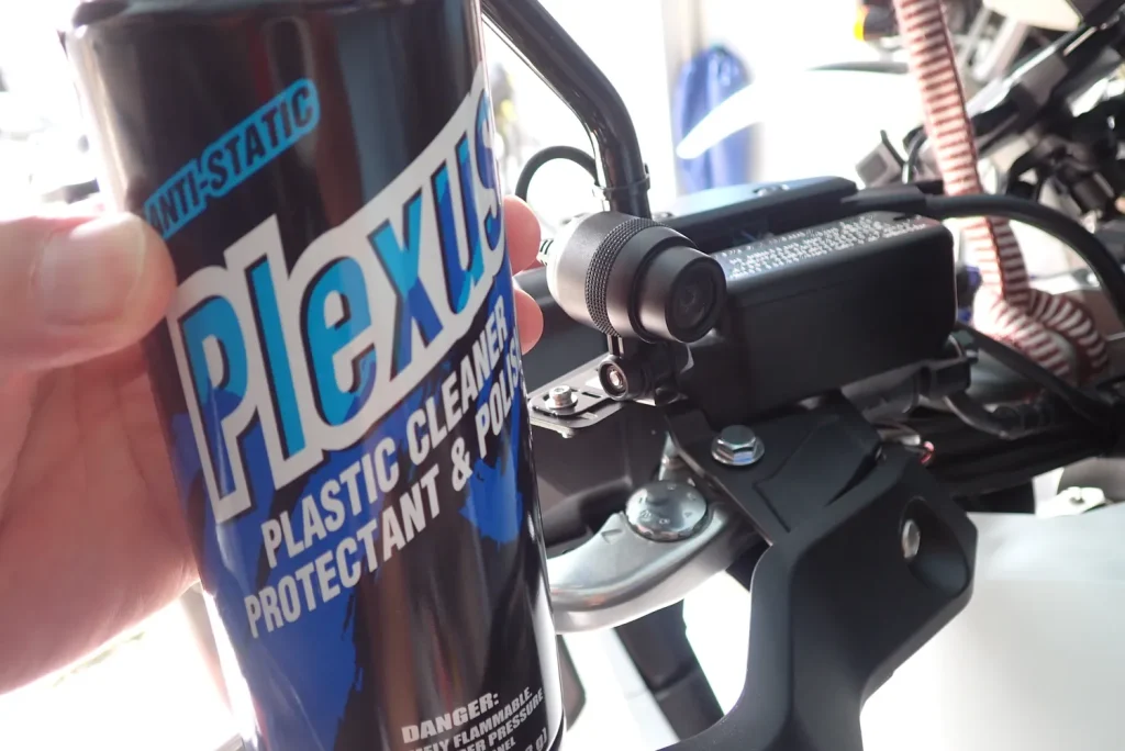 Cleaning the motorcycle dashcam lens using Plexus plastic cleaner and cloth