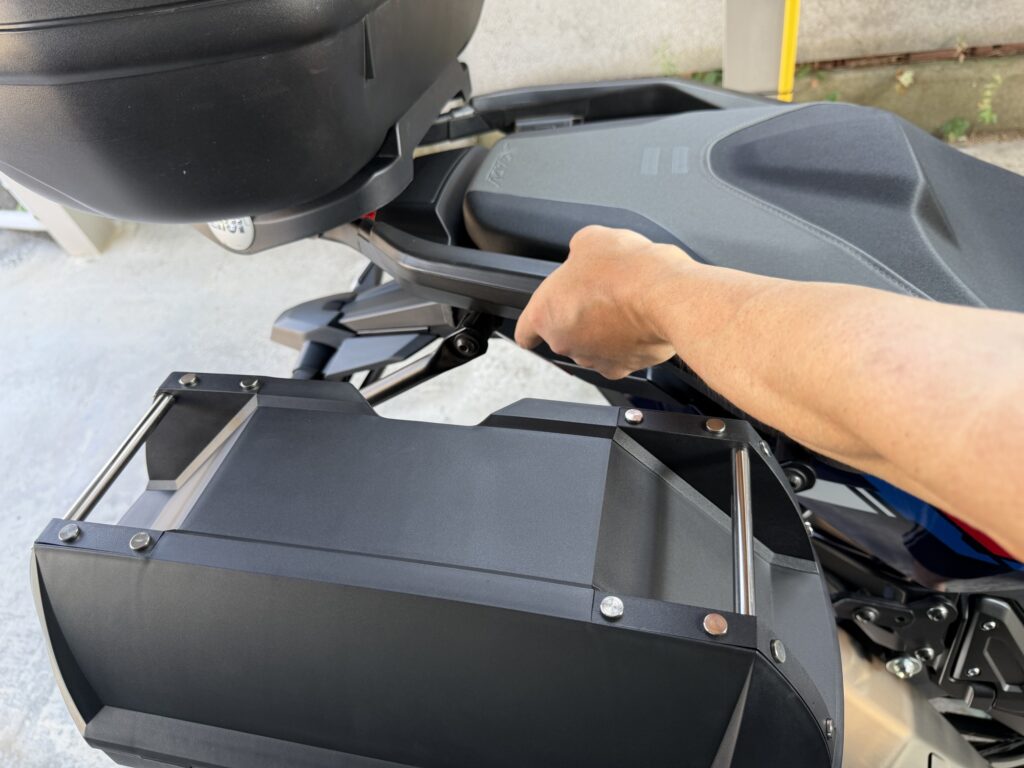 La mano impugna il maniglione di serie dell'X-ADV senza toccare la valigia