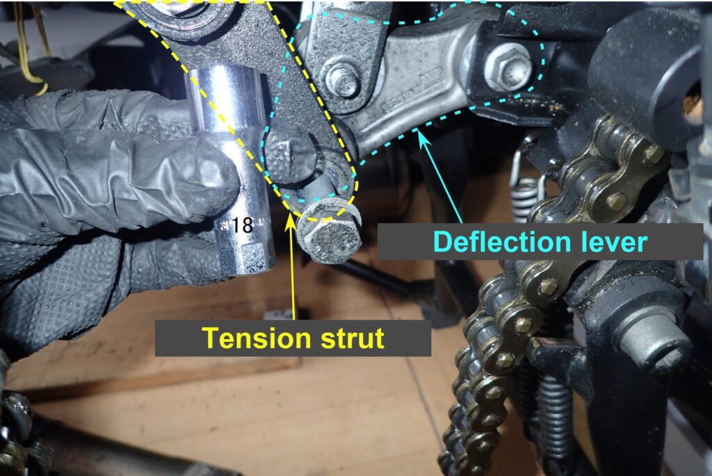 Removing the tension strut from the deflection lever on a BMW G650GS with an 18 mm socket