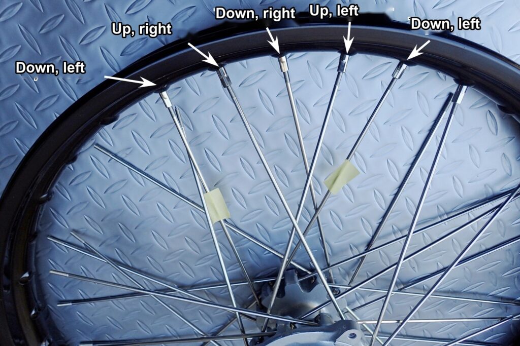 Four spokes loosely connected to the rim with nipples, checking the spoke and rim hole combinations (masking tape)