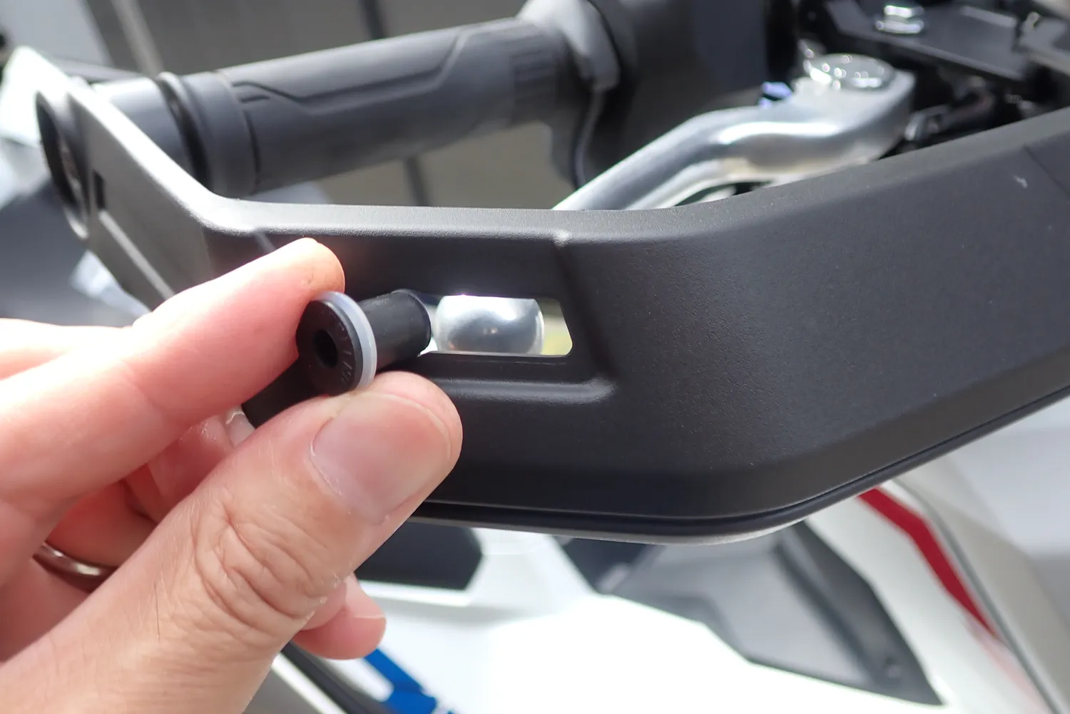 X-ADVのナックルガード外側の取付穴にウェルナットを差し込んでいる