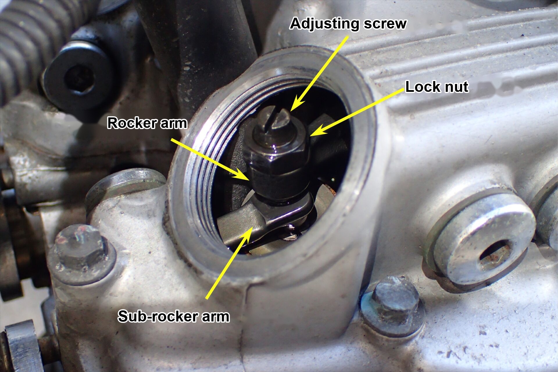 Inside the valve hole with the cap removed: the adjusting screw and lock nut for the tappet adjustment are exposed.